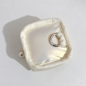 Detail of cream fabric earphone case with silver ring and pearl decoration