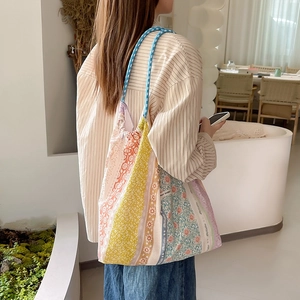 Dettaglio della borsa tote patchwork floreale con manici blu ed etichetta laterale