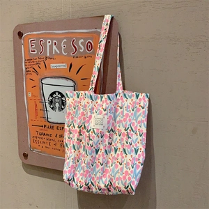 Détail du sac cabas floral en toile avec tulipes roses et étiquette blanche sur tissu