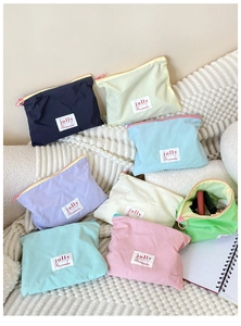 Macro detail of eight colorful macaron makeup bags showing zipper and jolly brand label