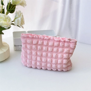 Detailed macro view of soft pink bubble textured fabric and ruffled edge on the makeup bag