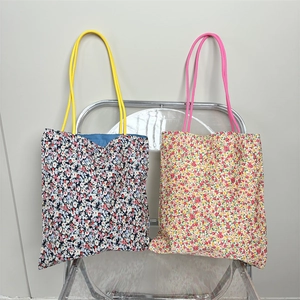 Macro shot of floral canvas tote bags with colorful rope handles hanging on a modern chair