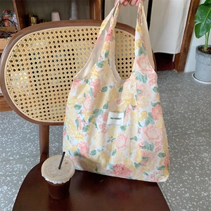 Détail de texture du sac cabas en toile fleurie sur une chaise rétro avec accessoires