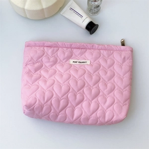 Detailed view of pink heart-quilted cosmetic bag with metal zipper and white fabric label