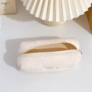 Close-up of off-white plush pencil case with soft faux fur texture and zipper detail