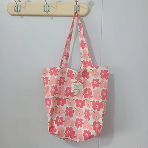 Détail du sac cabas en toile florale avec imprimé fleurs roses et étiquette tissée