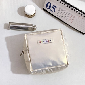 Close-up of pearl white makeup bag with colorful embroidered logo and metal zipper detail