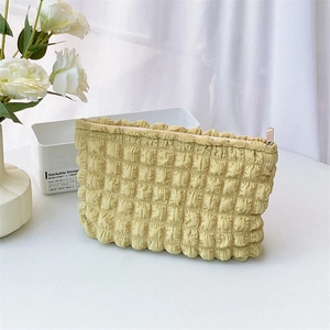 Detail of creamy yellow quilted cloud makeup bag with metallic zipper and bubble texture