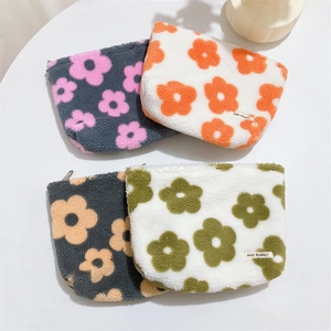 Close-up of four floral plush makeup bags with soft textures and metal zippers