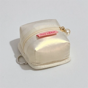 Detail of cream fabric earphone case with pearl zipper pull and metal hook attachment