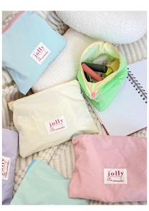 Flat lay of macaron-colored nylon makeup bags in assorted pastel tones on plush fabric