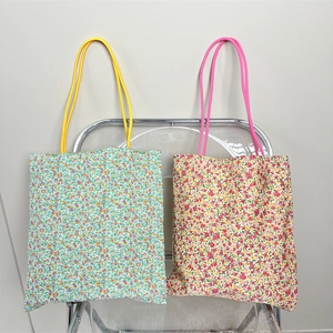 Detail of floral canvas tote bags with colorful rope handles in cool and warm flower patterns