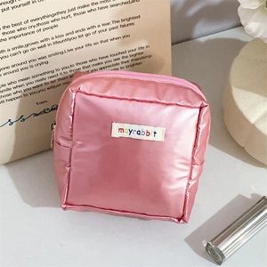 Close-up of a pink quilted cosmetic pouch with a metallic finish and zip closure