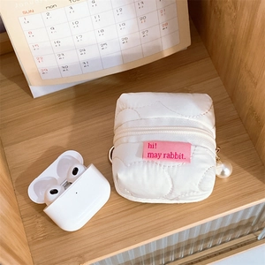 Detailed view of a white quilted earphone case with a pearl pendant and a metal clip