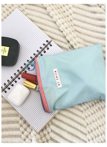 Vue détaillée de la trousse bleue avec fermeture éclair rose sur un carnet à carreaux