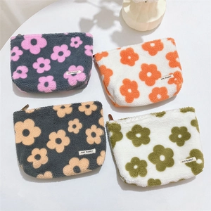 Close-up of fluffy floral plush cosmetic bags in four colors with secure metal zippers