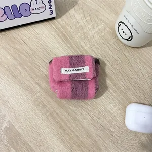 Macro-opname van gebreide gestreepte hoes voor AirPods Pro met May Rabbit-label op hout
