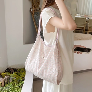 Dettaglio della borsa tote in tela floreale con tracolla rosa ed etichetta tessuta