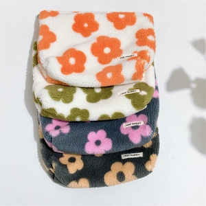 Detailed stack of floral fleece makeup bags in multiple colors with woven labels