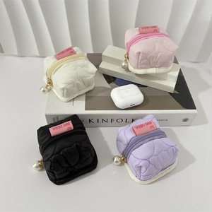Detailed macro view of mini quilted earphone pouches with pearl zipper charms in four colors