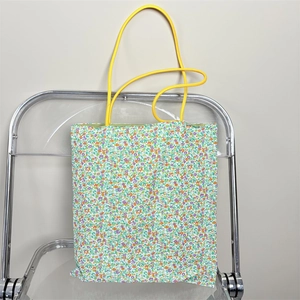 Detailed shot of floral canvas tote bag with vibrant yellow rope handles and green lining