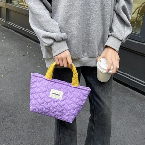 Detailed view of purple quilted heart pattern tote with contrasting yellow handles