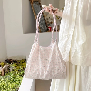 Dettaglio della borsa shopper floreale con motivi rosa e manici a corda intrecciata