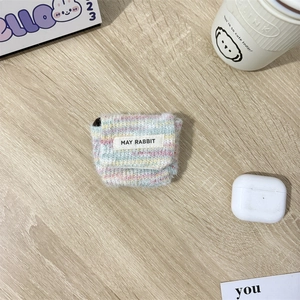 Detail van een gebreide oortelefoonhoes in pastelkleuren met MAY RABBIT-logo op hout