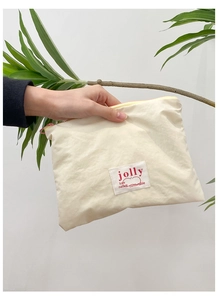 Close-up of off-white canvas makeup pouch with red jolly label and pink zipper detail