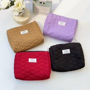 Close-up of quilted heart patterns on assorted cosmetic bags in four vibrant colors