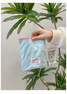 Gros plan d'une pochette en nylon bleu clair avec fermeture éclair rose et logo