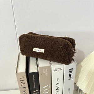 Brown sherpa fleece pencil case with mayrabbit label and silver zipper ring on books