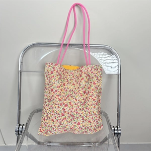 Detail of floral tote bag showing colorful print, pink rope handles and yellow lining