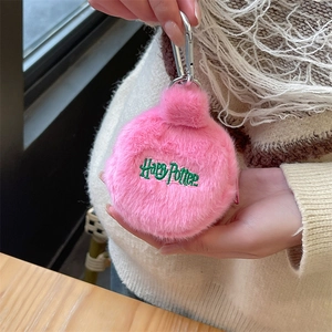 Close-up of pink plush mini pouch with green Harry Potter embroidery held by hand