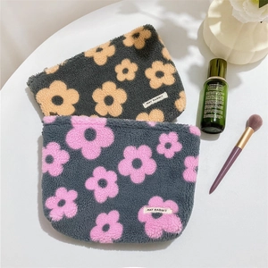 Close-up of fluffy floral makeup bags with soft plush texture and woven logo labels