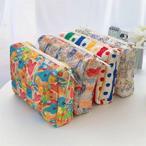 Detail of four quilted cotton makeup bags with floral and cartoon prints in a soft scene