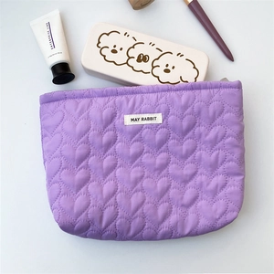 Detail of purple quilted makeup bag with heart pattern and May Rabbit woven label