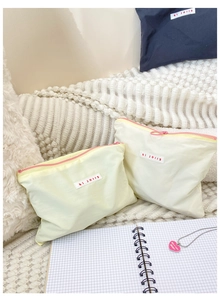 Detail of beige zipper pouches in two sizes with pink zippers and hi jolly label