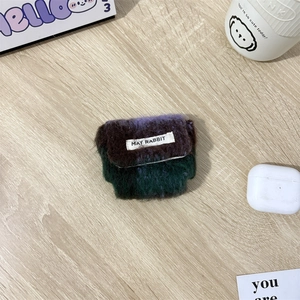 Detailopname van een paars gebreid MAY RABBIT oortelefoonhoesje met merklogo op tafel