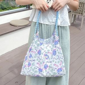 Foto all'aperto di una borsa tote in tela a fiori con manici a quadretti blu e logo