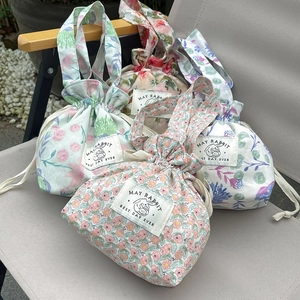 Detail view of floral drawstring canvas bags with elegant rabbit labels in natural garden