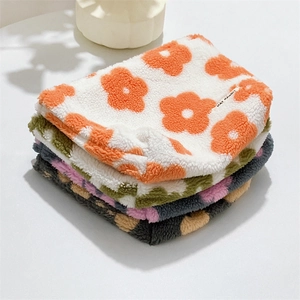 Close-up of soft plush cosmetic bag featuring colorful floral patterns and brand label