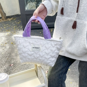 Close-up of heart quilted white canvas handbag with purple handles and zipper closure