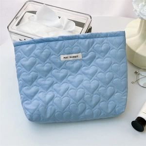 Close-up of light blue quilted cosmetic bag with heart pattern and May Rabbit label