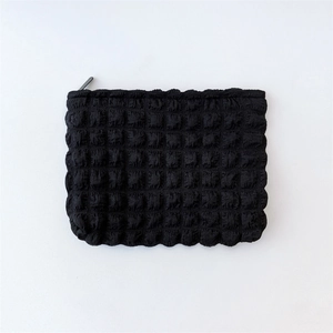 Detailed view of the black popcorn texture and zipper on this cloud cosmetic pouch