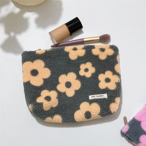 Close-up of soft grey fleece makeup bag featuring orange floral patterns and zipper detail