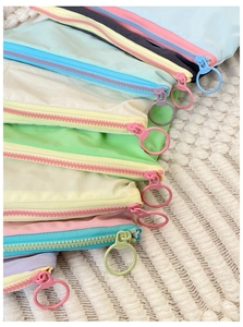 Macro view of macaron colored storage bags with large zippers and ring pullers