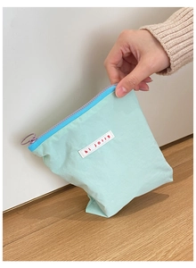 Détail de la pochette en toile vert menthe avec étiquette hi jolly et zip bleu vif