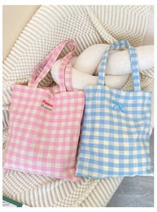 Detail of pink plaid canvas bag with Hopeless Romantic embroidery and blue bow accent
