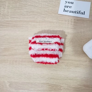 Detail van rood-wit gestreept pluchen tasje met MAY RABBIT label op houten tafel